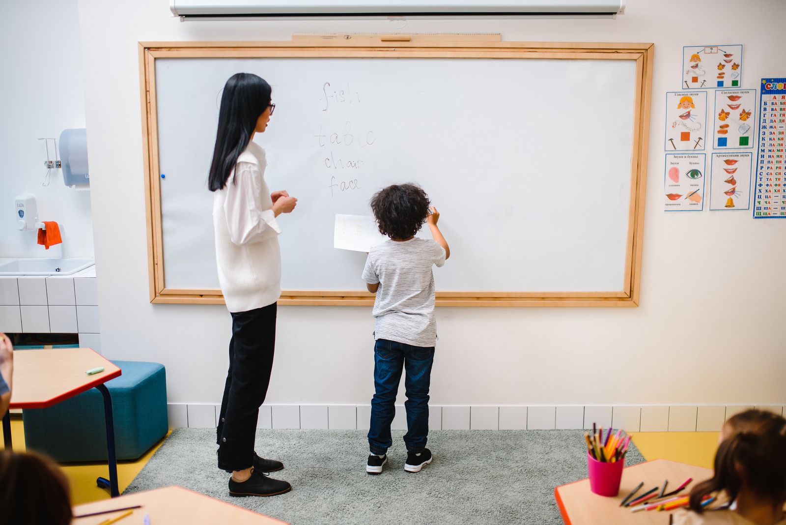 A teacher helping an elementary student at the classroom board